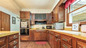Une cuisine avec des meubles de rangement en bois, un four à micro-ondes, un grille-pain et un tapis rouge sur le sol.