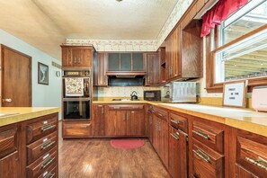 A kitchen with wooden cabinets, a microwave, a toaster, and a red rug on the floor. - Harmony Hills -- 3 bedroom country home (Bloomington)