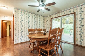 Ein Esszimmer mit Holztisch und -stühlen, einem Deckenventilator und blumigem Wandpapier.
