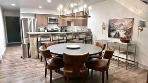 Una cocina moderna con una isla central, electrodomésticos de acero inoxidable y un comedor con una mesa redonda y sillas.