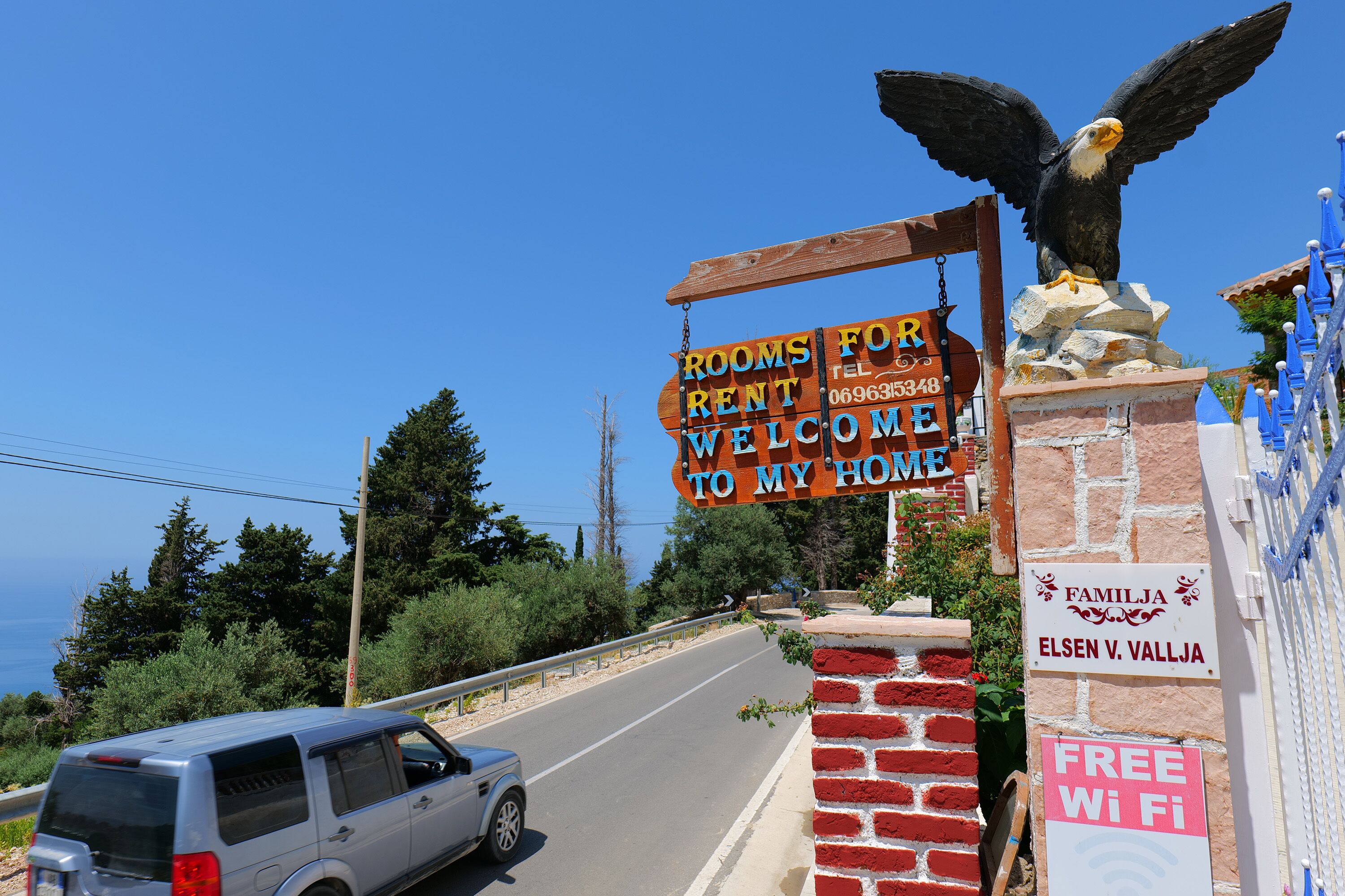 Ein Schild empfängt Besucher, zeigt eine Vogelstatue, ein Schild mit 'Free WiFi' und ein Schild mit der Aufschrift 'Familia'.