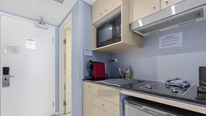 Una cocina compacta con microondas, hervidor rojo, lavabo y lavavajillas.