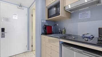 A compact kitchen with a microwave, a red kettle, a sink, and a dishwasher.