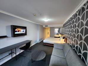Relax in a stylish room with a flat-screen TV, comfortable sofa, and a neatly made bed.