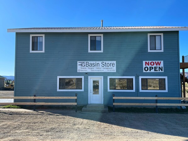 A two-story building with a sign indicating it's a TG Basin Store offering snacks, burgers, cabins, and a campground. - 1 Room Cabin in Dry Creek Basin. (Norwood)