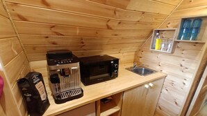 Een kleine keuken met een koffiezetapparaat, magnetron en spoelbak.