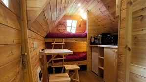 Een knus vakantiehuisje met een slaapzolder, een kleine keukenhoek en een houten trap.