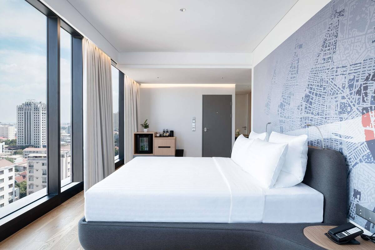 Une chambre d’hôtel moderne avec un grand lit, un bureau et une vue sur la ville.