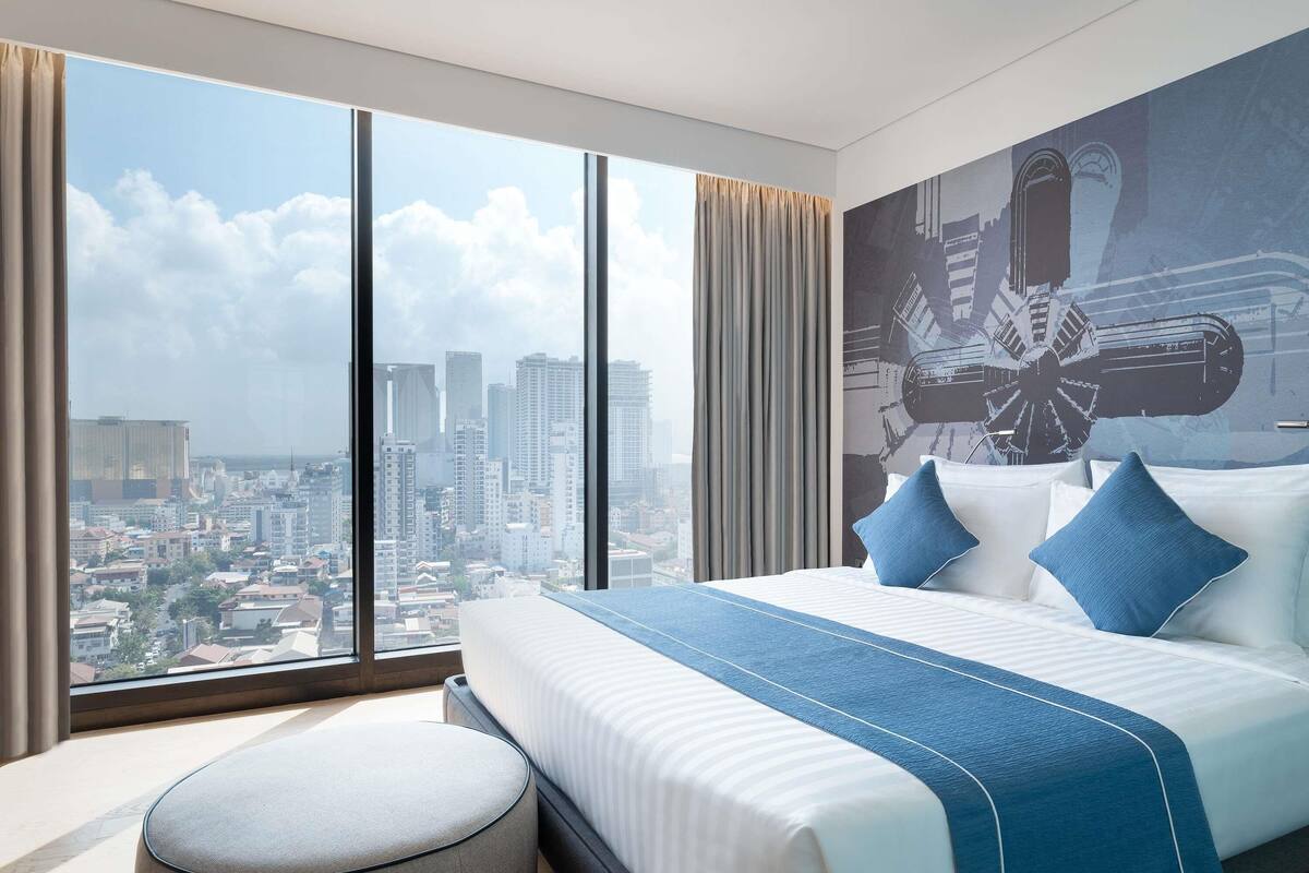 Une chambre d’hôtel dotée d’un grand lit, offrant une vue sur le paysage urbain et présentant un design moderne.