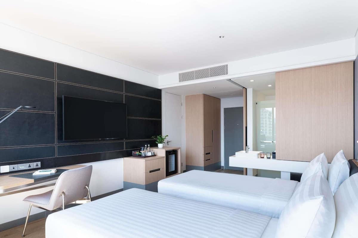 A modern hotel room with a bed, a desk, a TV, and a bathroom.