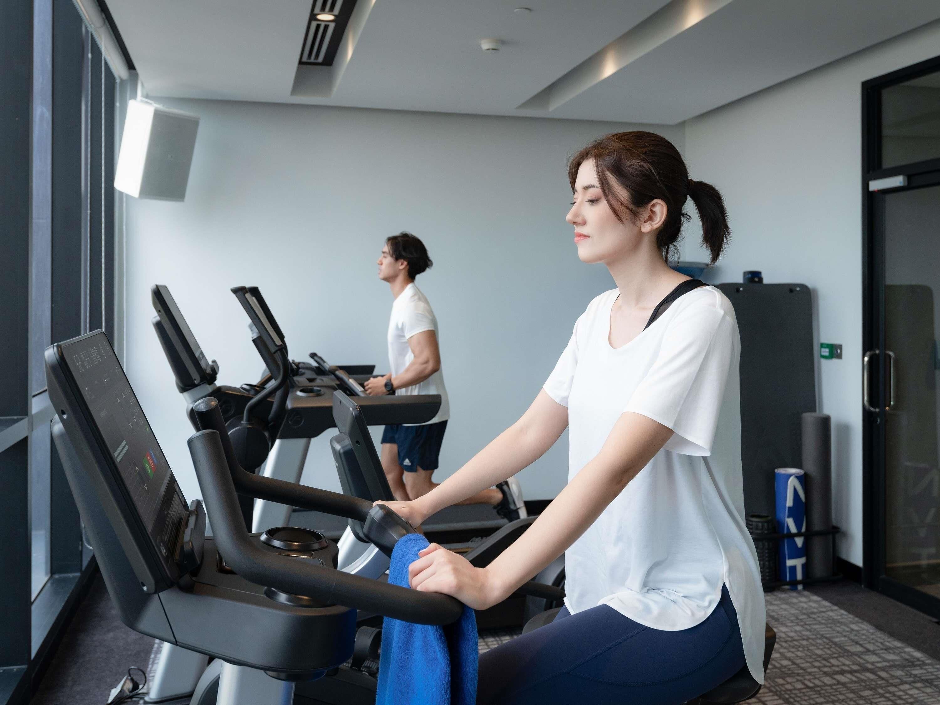 Ein Fitnessstudio mit Laufbändern und einer Person, die eines benutzt.