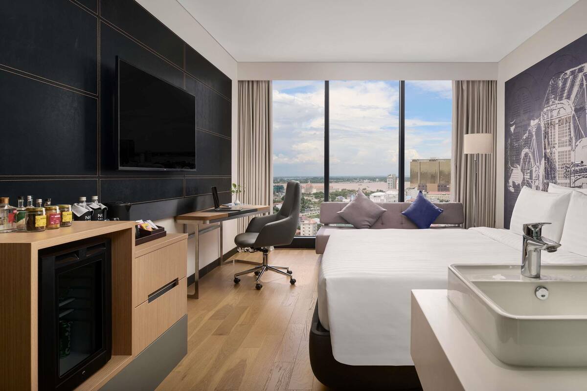 Une chambre d’hôtel avec un lit, un bureau et une télévision.