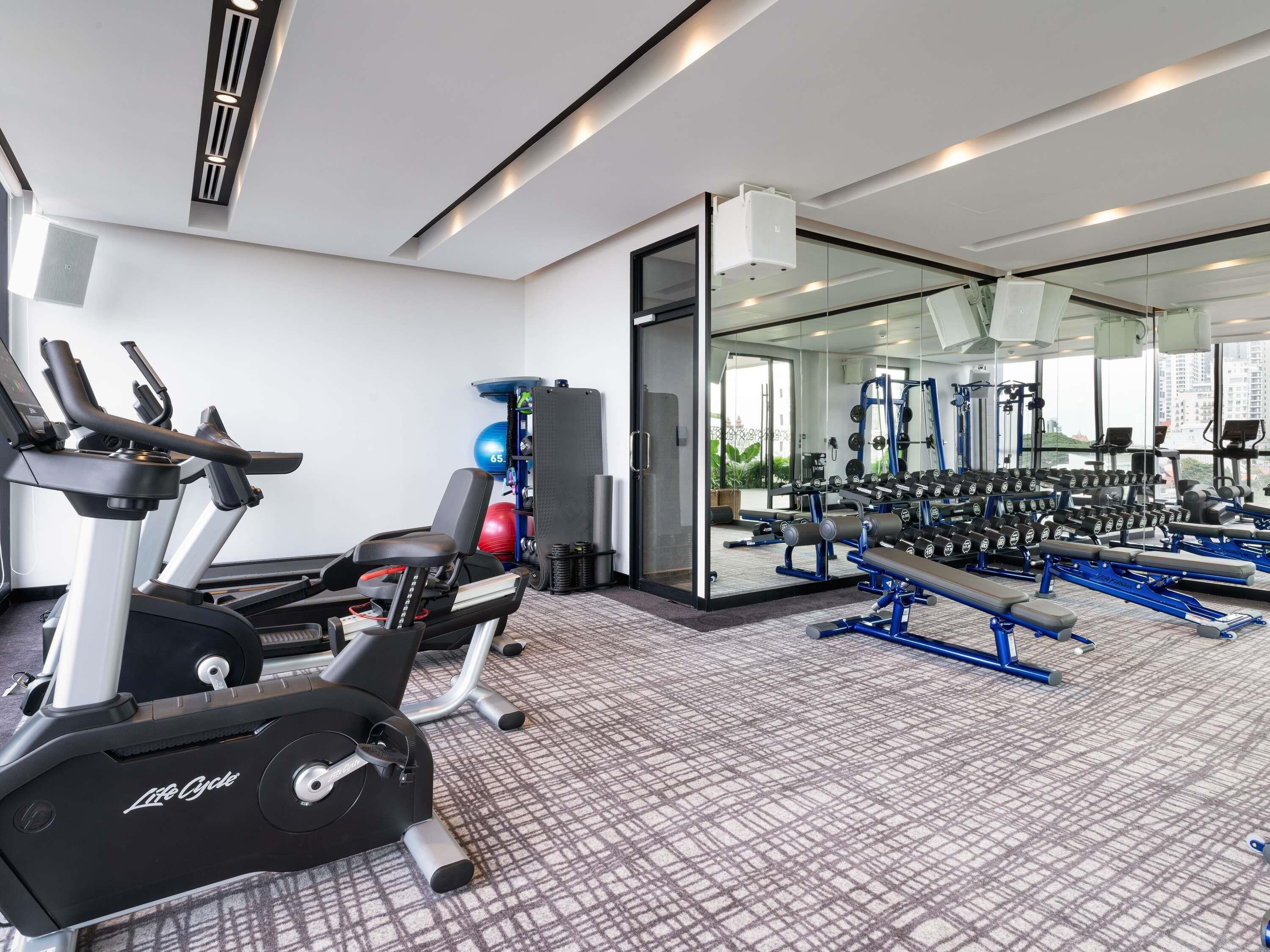 A gym with treadmills, weight machines, and a mirrored wall.