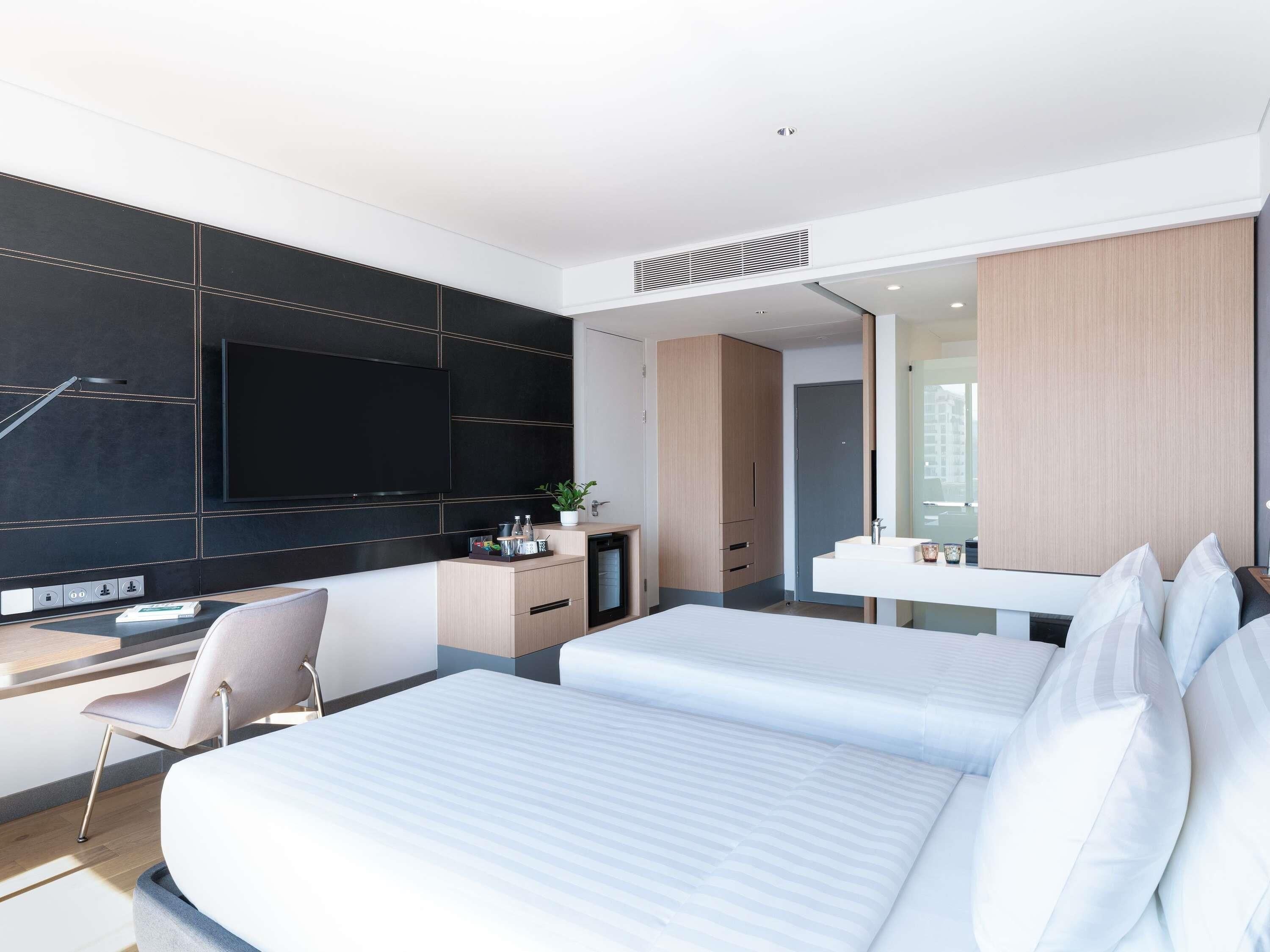 Een moderne hotelkamer met een bed, bureau, televisie en badkamer.