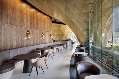 A modern interior with a wooden wall, glass partitions, and seating areas.