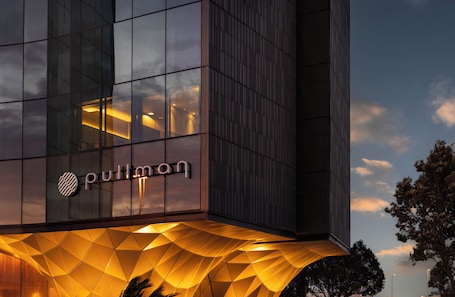 A modern building with a glass facade, a prominent logo, and a geometric patterned entrance.