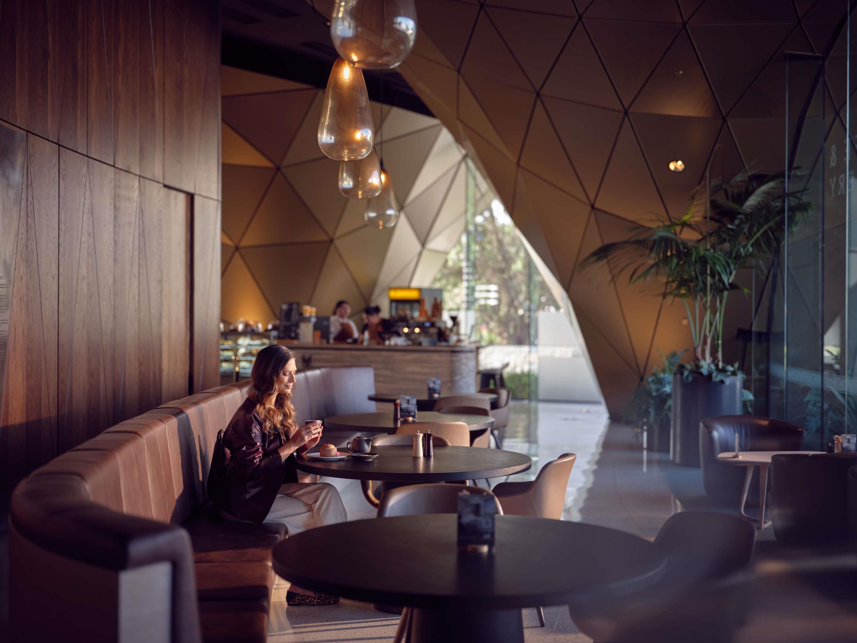 A modern interior with a geometric ceiling, seating areas, and a bar counter.