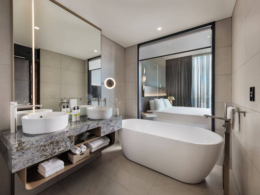 A modern bathroom with a freestanding bathtub, two sinks, a large mirror, and a vanity with storage.