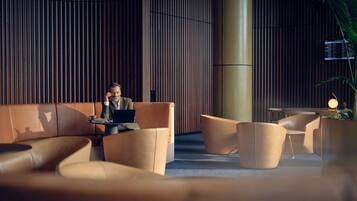 Un espace détente moderne avec des canapés en cuir, un ordinateur portable posé sur une table et une grande colonne cylindrique.