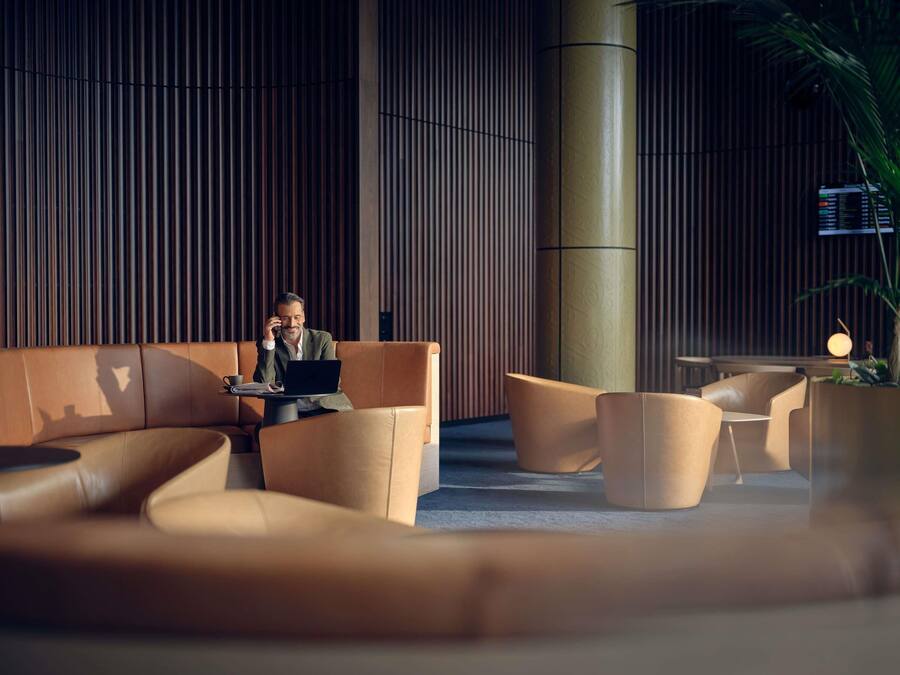 A modern lounge area with leather sofas, a laptop on a table, and a large cylindrical column.