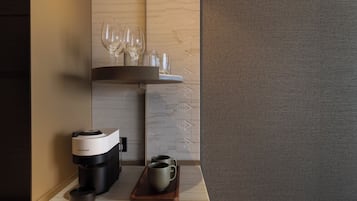 A coffee machine, two mugs, and wine glasses on a counter.