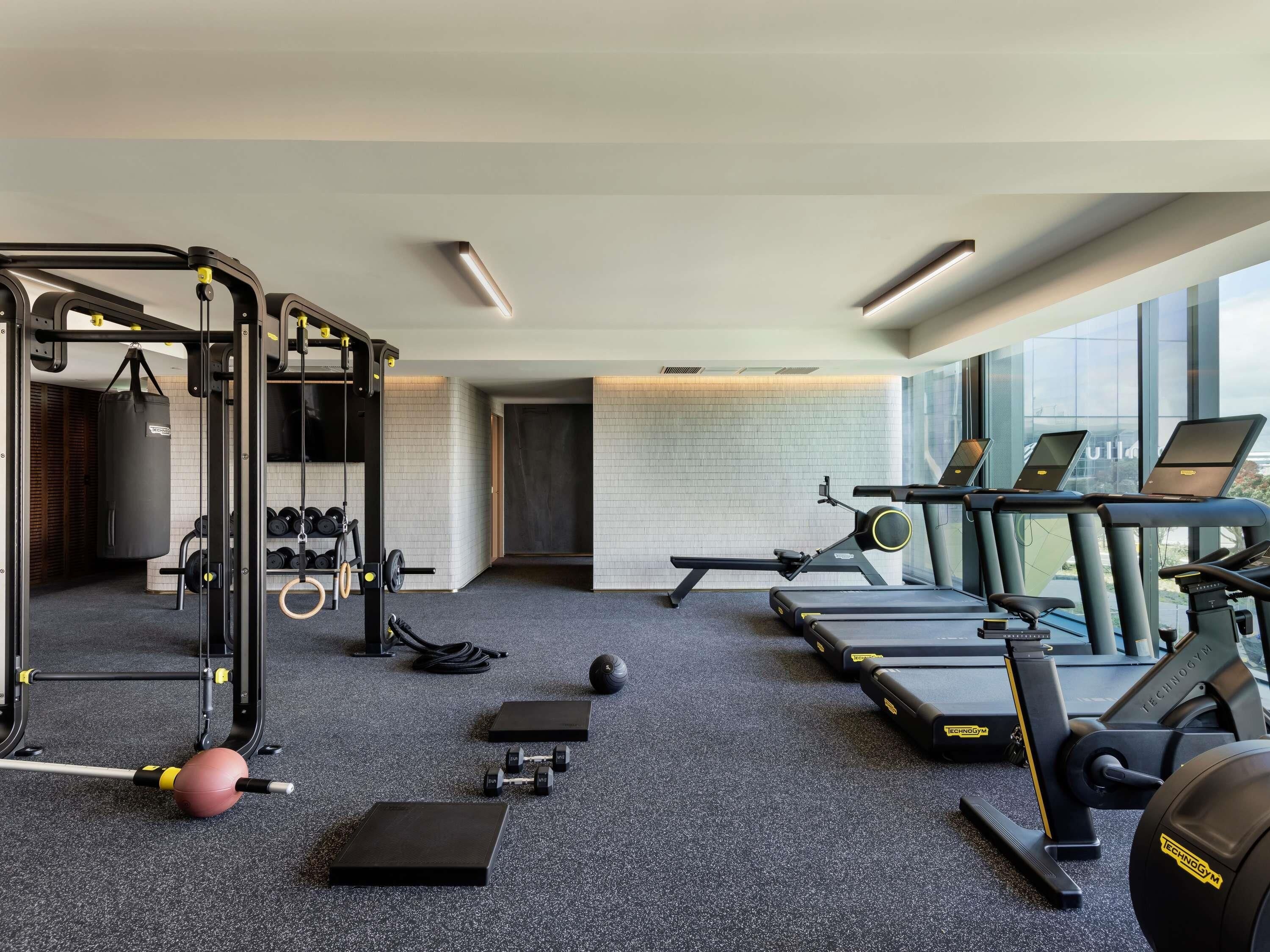 Ein Fitnessstudio mit Laufbändern, Krafttrainingsgeräten und einem Boxsack.