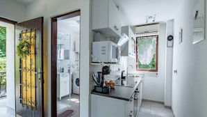 A modern kitchen with white cabinets, a microwave, and a sink. There is a window with a view of greenery outside. - Holiday apartment close to the center (Njivice)