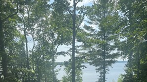 A grassy area with trees and a view of a body of water. - Lakefront Log Cabin with Contemporary touches (Carp Lake)