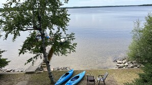 A lakeside deck with kayaks, a fire pit, and outdoor seating. - Lakefront Log Cabin with Contemporary touches (Carp Lake)