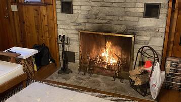 Ein gemütliches Wohnzimmer mit Kamin aus Stein, Holzwänden und einer komfortablen Sitzecke.