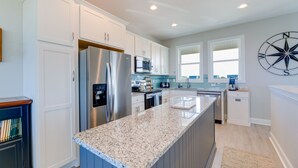 Una cocina moderna con armarios blancos, electrodomésticos de acero inoxidable y encimera de granito.
