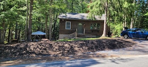 A small cabin with a front porch, surrounded by trees. - PET FRIENDLY -LOCATED BETWEEN LAKE PLACID AND SARANAC LAKE WITH PONTOON RENTALS (Saranac Lake)