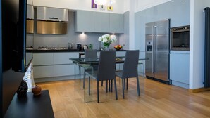 A modern kitchen with a dining area, featuring a glass table, chairs, and a stainless steel refrigerator. - notaMi - Romolo Space Navigli (Milan)