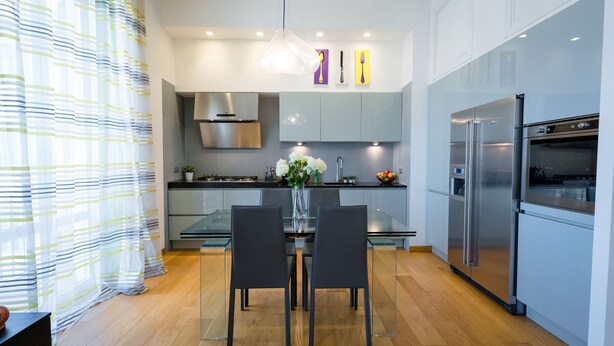 A modern kitchen with a glass dining table, two chairs, stainless steel appliances, and a vase with flowers. - notaMi - Romolo Space Navigli (Milan)