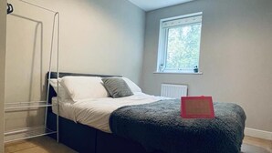 A bedroom with a bed, a window, a radiator, and a ceiling light. - Stunning 2-bed Apartment in Crawley (Crawley)