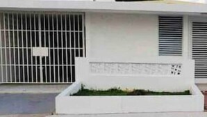 Un bâtiment moderne à l’extérieur blanc, doté d’une entrée sécurisée et d’un petit jardin.
