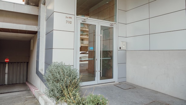 A modern building entrance with a glass door, a visible number "702", and a small potted plant in the foreground. - Bright Apartment by Homing (Porto)