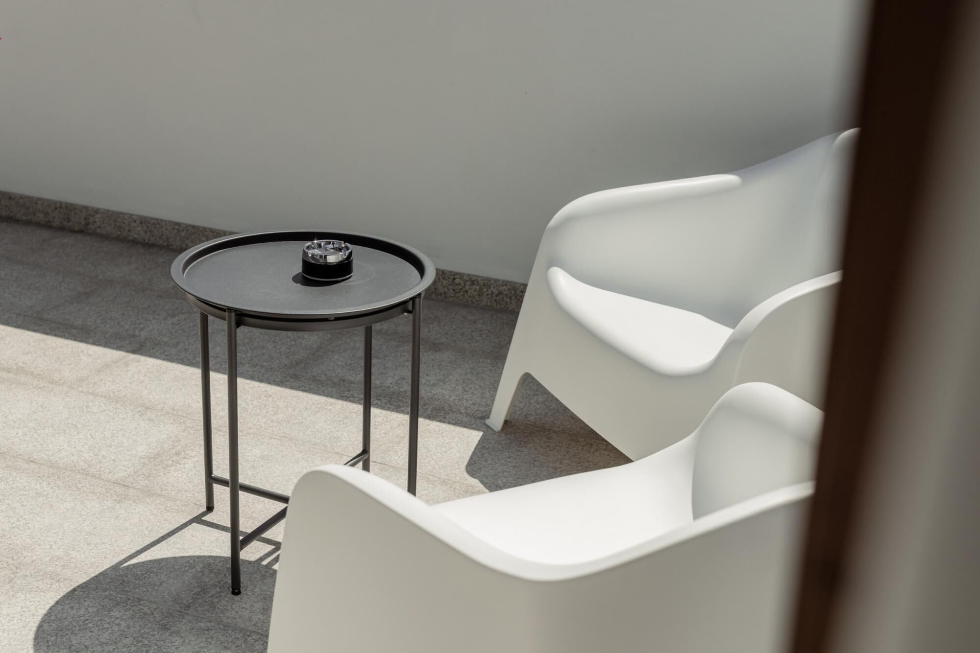 A small outdoor seating area with a round table and two white chairs.