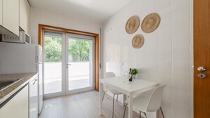 Eine moderne Küche mit weißer Arbeitsplatte, einer eingebauten Mikrowelle und einer Schiebetür zu einem Balkon.