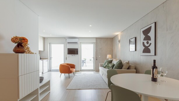 Una sala de estar moderna con sofá, mesa de comedor y televisor.