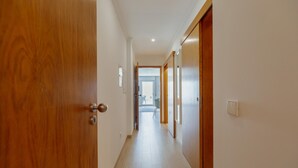 Un pasillo con puertas de madera y vistas a una habitación con una silla y una mesa.