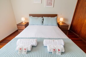 A hotel room with a large bed, two bedside lamps, and a set of towels on the bed. - Modern Cedofeita by Homing (Porto)