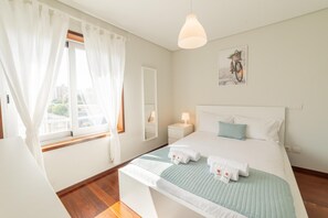 A hotel room with a bed, a bedside table with a lamp, a window with curtains, and a wall-mounted picture. - Modern Cedofeita by Homing (Porto)