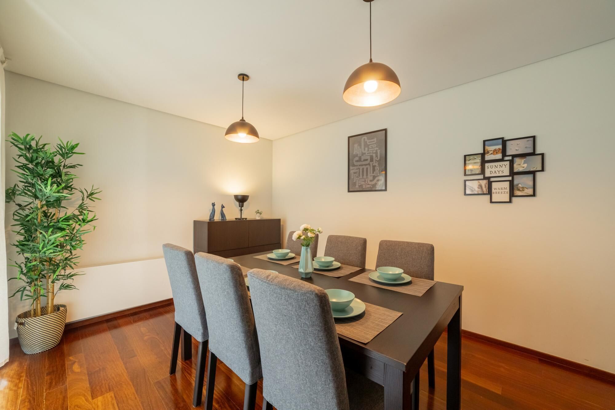 Un coin repas avec une table en bois, des chaises grises et une plante en pot.