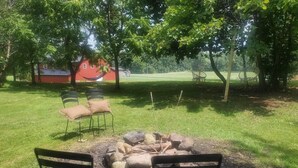 Un espacio de estar al aire libre con sillas de metal y un brasero rodeado de rocas.