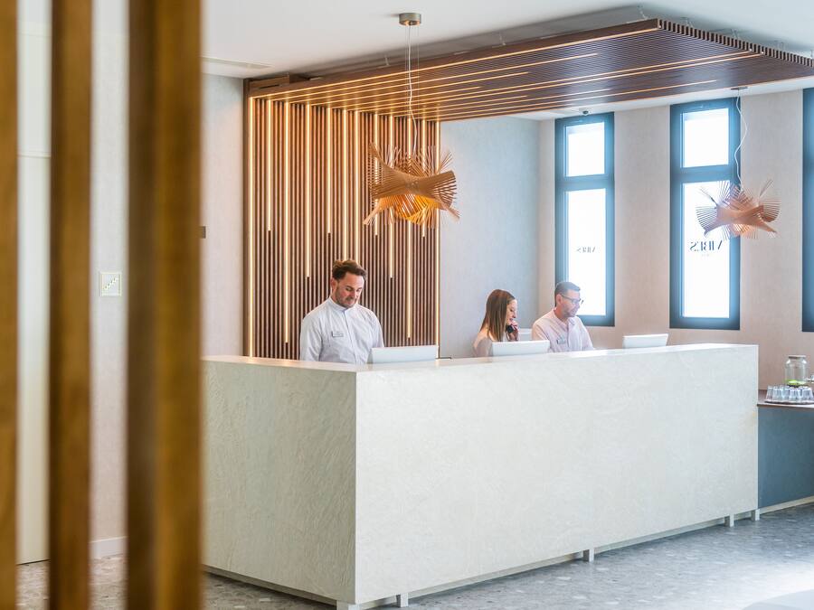 Un área de recepción de diseño moderno, con mostrador, listones verticales de madera e iluminación colgante.
