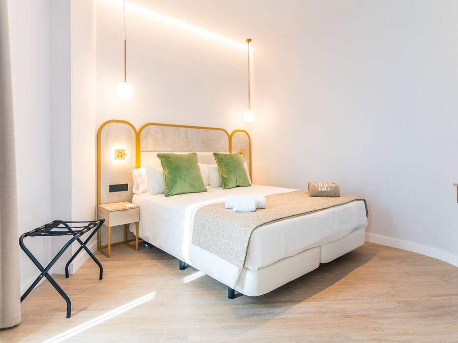 Un dormitorio moderno con cama, mesitas de noche y una pequeña mesa con lámpara.