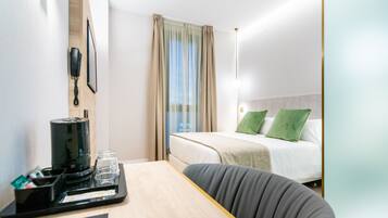 Une chambre d’hôtel avec un lit, un bureau doté d’une machine à café, un téléphone et une fenêtre avec des rideaux.
