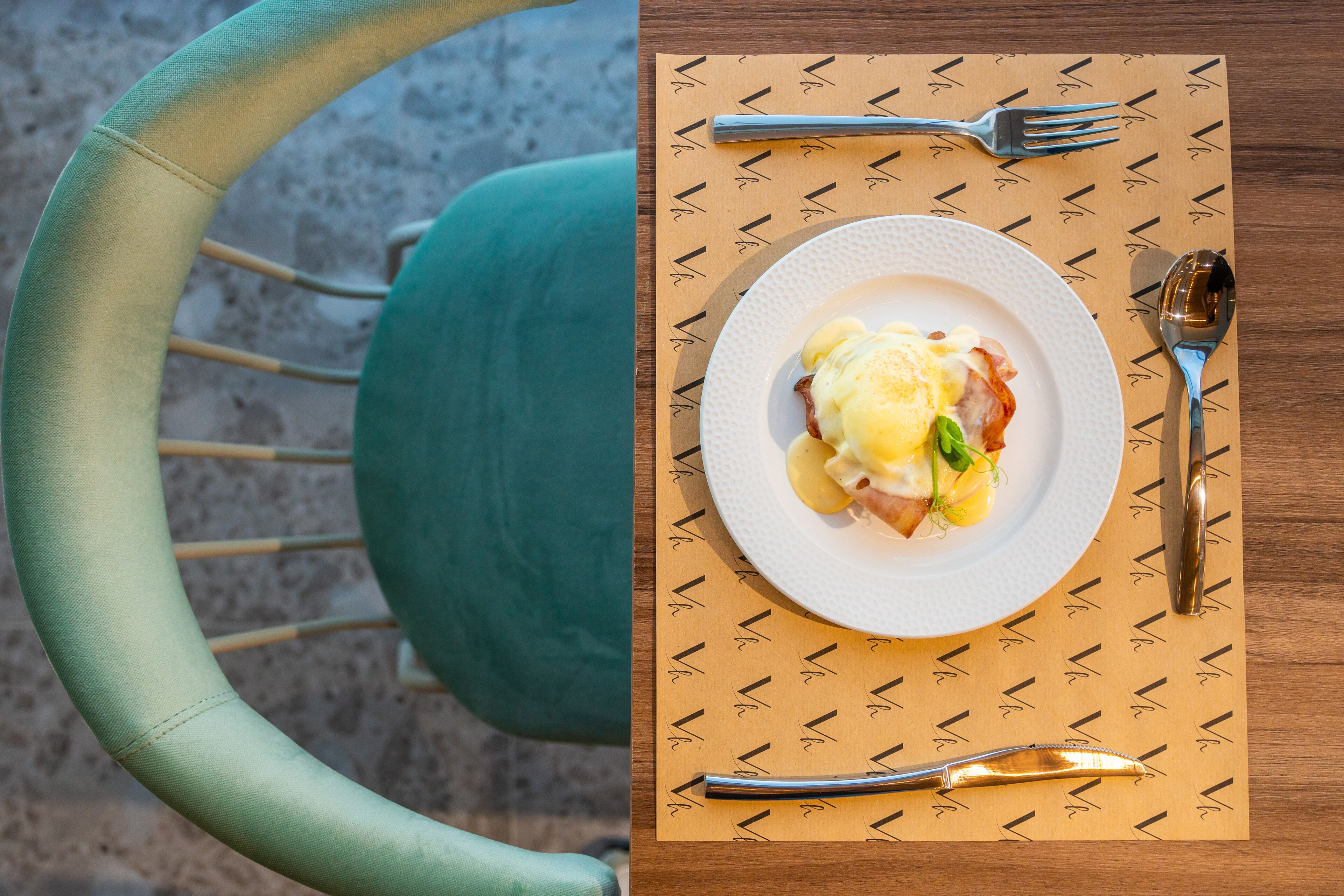 Une table à manger avec une assiette de nourriture, des couverts et un set de table à motifs.