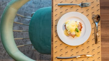 A dining table with a plate of food, cutlery, and a patterned placemat.